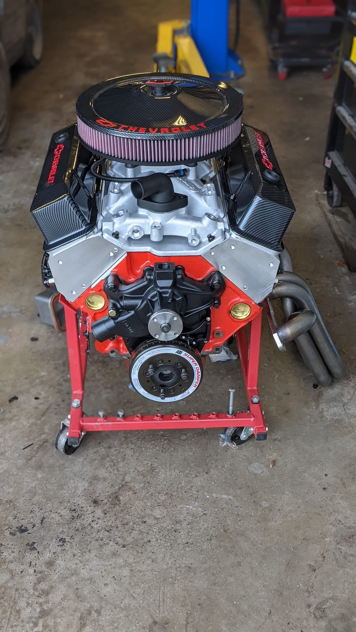 Fully assembled small-block Chevy on a red engine stand with an EFI intake manifold, round air cleaner, and shorty headers, ready to install