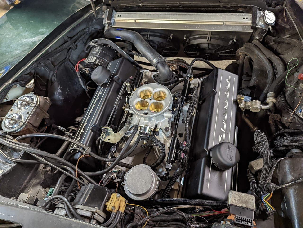 Engine bay of the 1974 Corvette mid-build with the EFI intake manifold and throttle body installed on the small-block, radiator and hoses in place