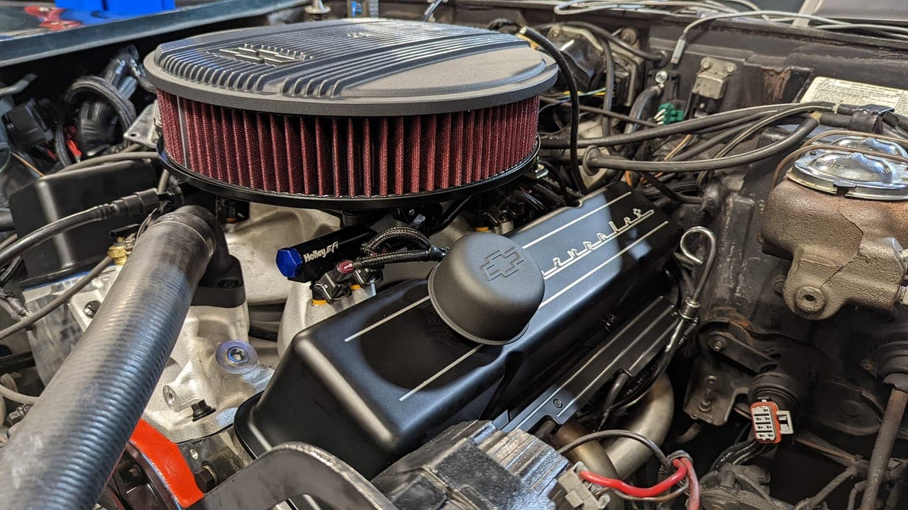 Finished engine bay of the 1974 Corvette with a round red air-filter element on top of the EFI small-block, hood open
