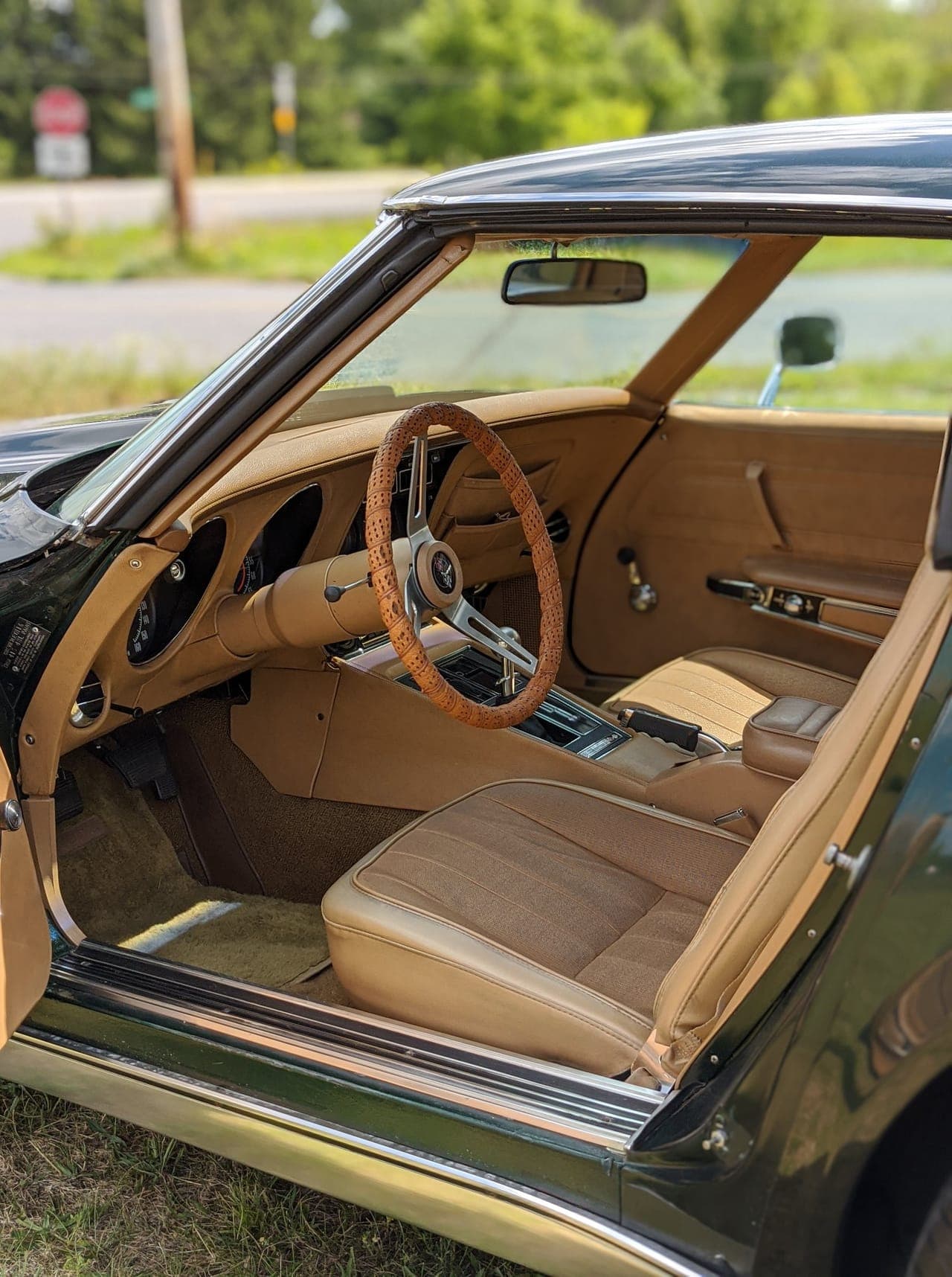 Tan saddle leather interior of the 1974 Corvette with the factory wood-rimmed steering wheel and center console, door open
