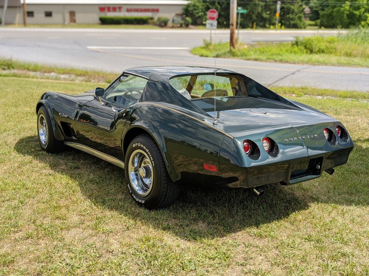 Rear three-quarter view of the finished dark green 1974 Corvette on a lawn showing the round taillights and Corvette badge