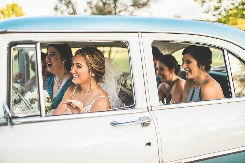 Bride and bridesmaids laughing together inside the restored 1955 Ford Fairlane