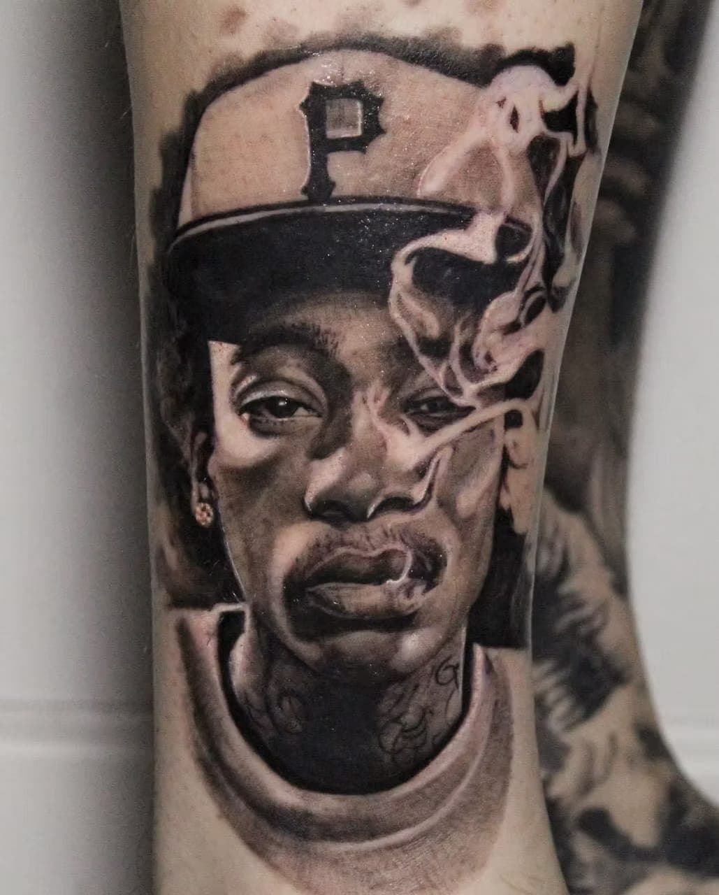 Black-and-grey realism portrait tattoo of a man in a Pittsburgh baseball cap, with smoke detail, by 5 Pound Gummy Tattoo Collective