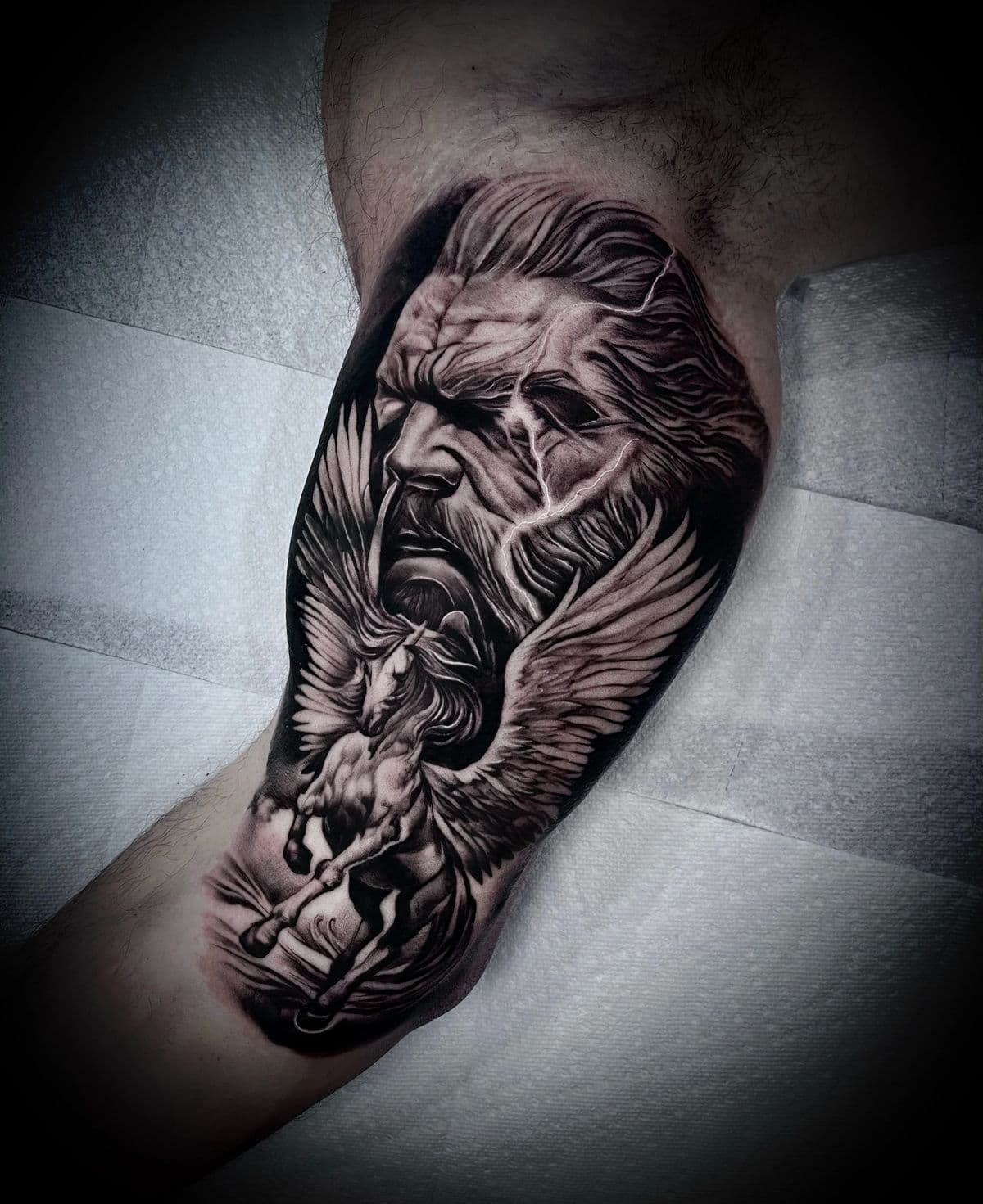 Black-and-grey realism tattoo of a bearded figure with a winged horse, by an artist at Capital Tattoo Company
