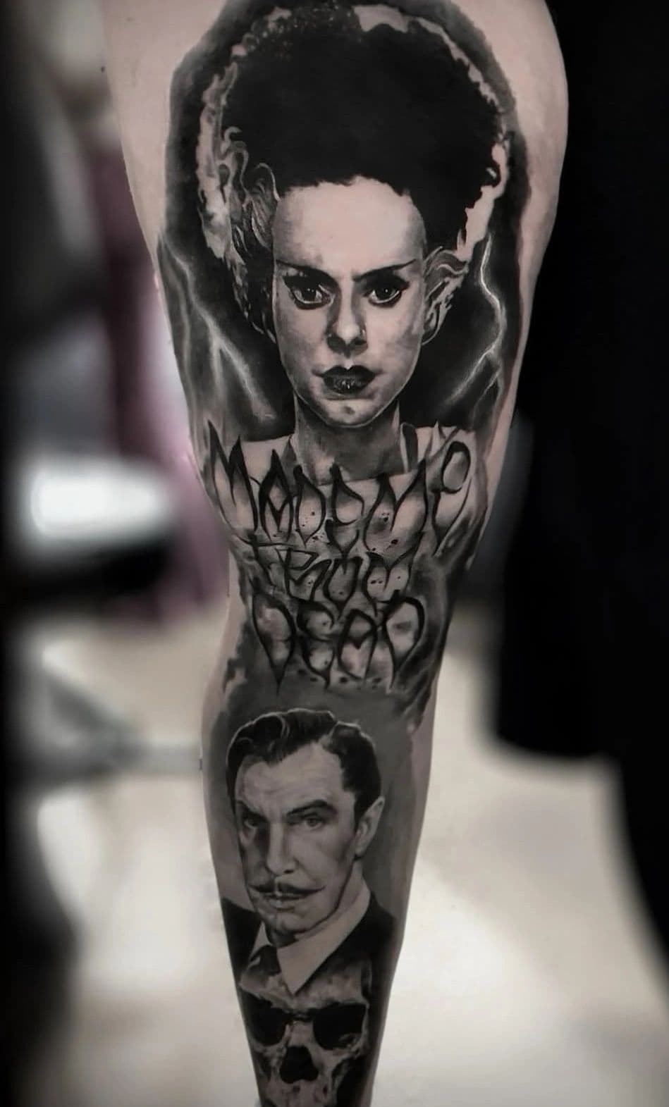 Horror-themed black-and-grey leg sleeve with portrait work, by an artist at Capital Tattoo Company