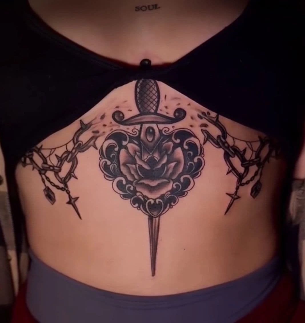 Neo-traditional black-and-grey dagger-and-rose chest piece, by an artist at Capital Tattoo Company
