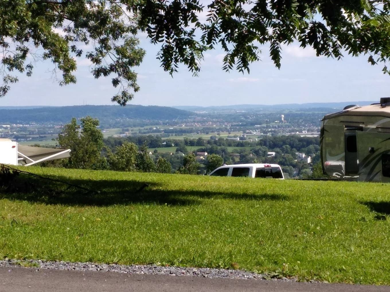 An open hilltop "Plateau" campsite at Starlite Camping Resort with a fifth-wheel RV and SUV, looking out over the Lancaster County valley and farmland