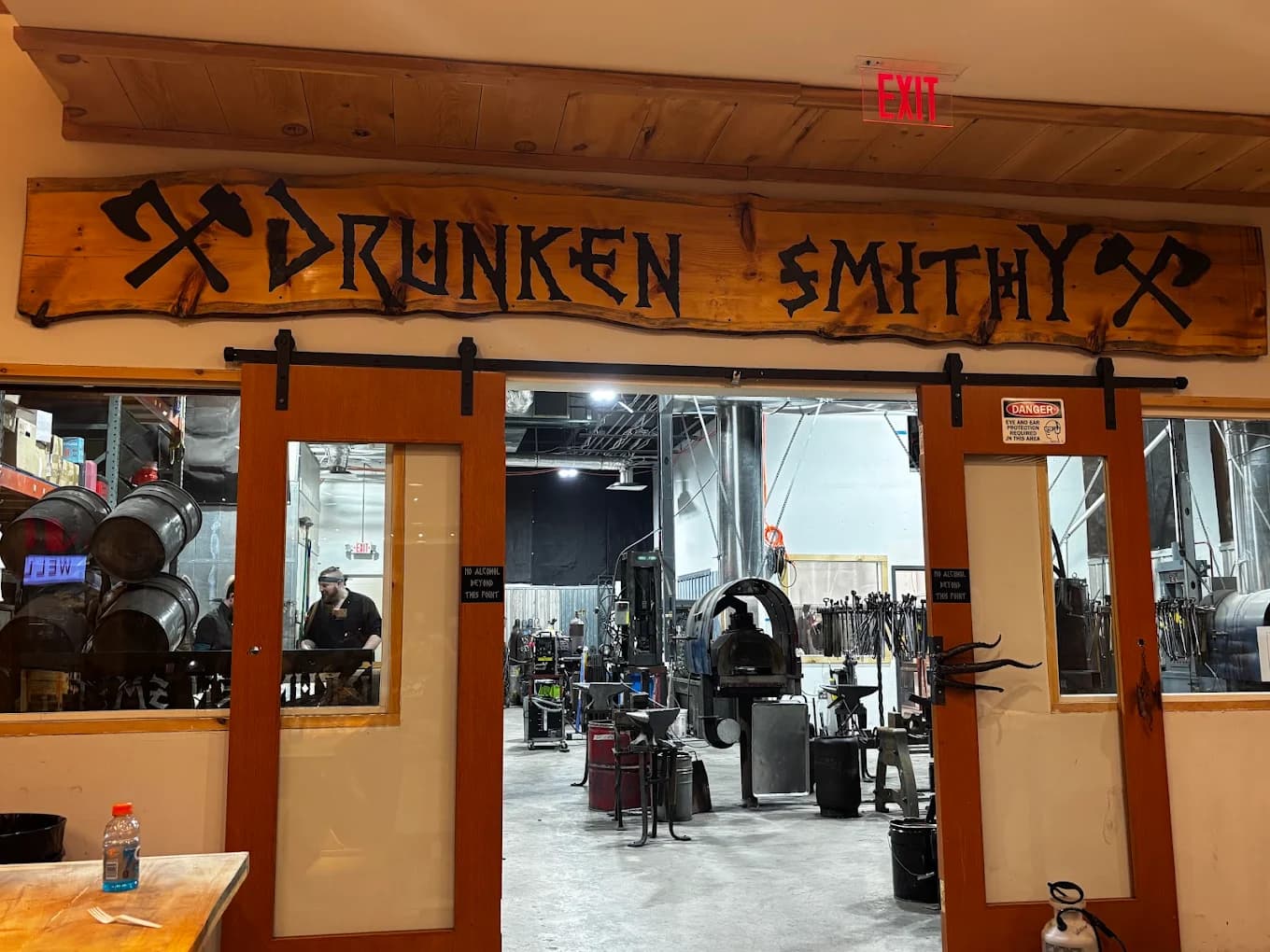 A reclaimed-wood 'DRUNKEN SMITHY' sign with crossed axes over the forge entrance at Lebanon Valley Mall in Lebanon, PA