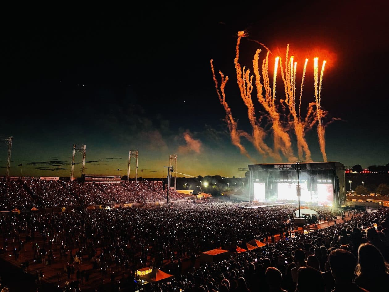 A packed nighttime concert crowd at Hersheypark Stadium with fireworks over the main stage