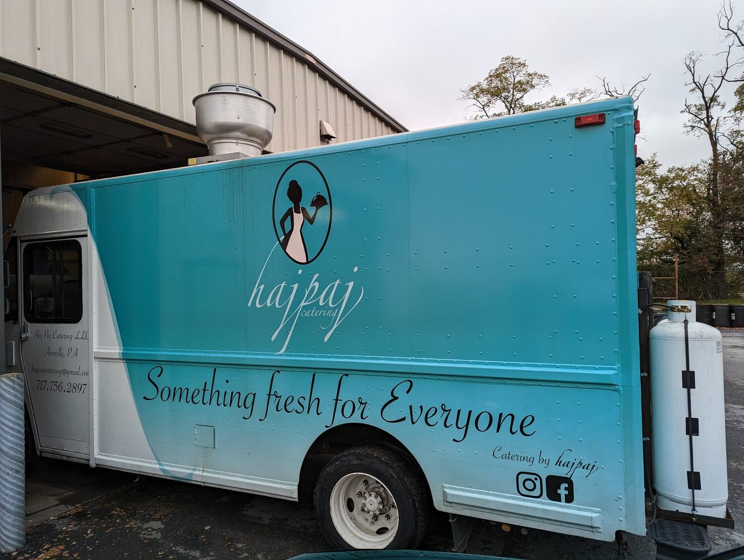 Haj Paj Catering food truck with its roof exhaust hood and propane tank outside the NextGen AutoWorks shop in Grantville, PA
