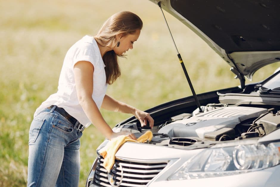 Driver checking vehicle fluids under an open hood before a summer road trip near Grantville PA