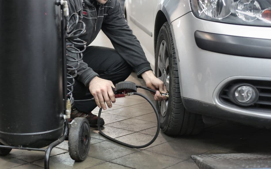 Mechanic inspecting and adjusting tire pressure in an auto repair shop near Grantville PA.