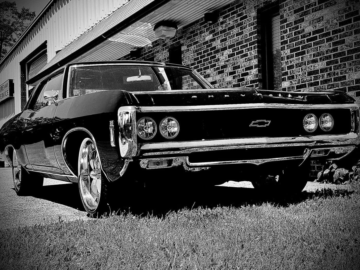 Ferg's black 1969 Chevrolet Impala, owned by Capital Tattoo Company, on custom wheels — photographed in black and white