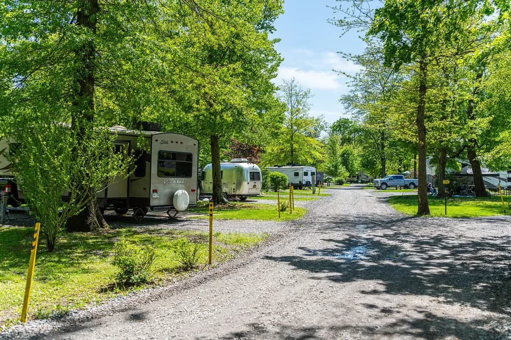 Shaded gravel campsites with RVs along a tree-lined road at the Jonestown KOA near Hershey, PA